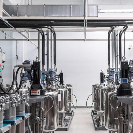 Panoramic photo of gray metal pipes and tanks. Chemistry and medicine production. Pharmaceutical factory. Interior of a high-tech factory, modern production.
